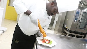 A chef in a professional kitchen preparing food. - Sainte Famille Hotel (Kigali)