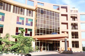 A multi-story building with a modern architectural design, featuring large windows and a central entrance with a covered area. - Sainte Famille Hotel (Kigali)