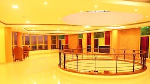 A spacious lobby with a central circular area, seating arrangements, and large windows. - Sainte Famille Hotel (Kigali)