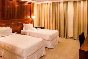 A hotel room with two beds, a wooden headboard, a desk, and a lamp. - Sainte Famille Hotel (Kigali)