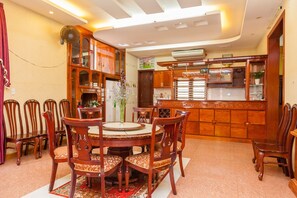 A dining area with a round table and chairs, wooden cabinets, and a kitchen area with a countertop and sink. - Villa Binh Minh (Ho Chi Minh City)