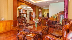A spacious, elegantly furnished dining area with a large wooden table, ornate chairs, and a vase of flowers. - Villa Binh Minh (Ho Chi Minh City)