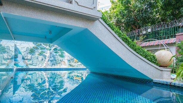 A swimming pool with a tiled design, a stone wall, and a metal fence. - Villa Binh Minh (Ho Chi Minh City)