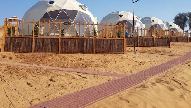 Una hilera de tiendas de forma abovedada con una valla de madera en un paisaje desértico.