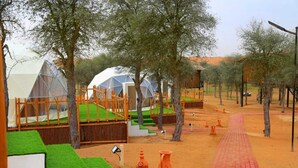 Un camping con tiendas en forma de cúpula, juegos de madera y un camino pavimentado.