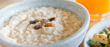 A bowl of oatmeal with raisins on a wooden table.