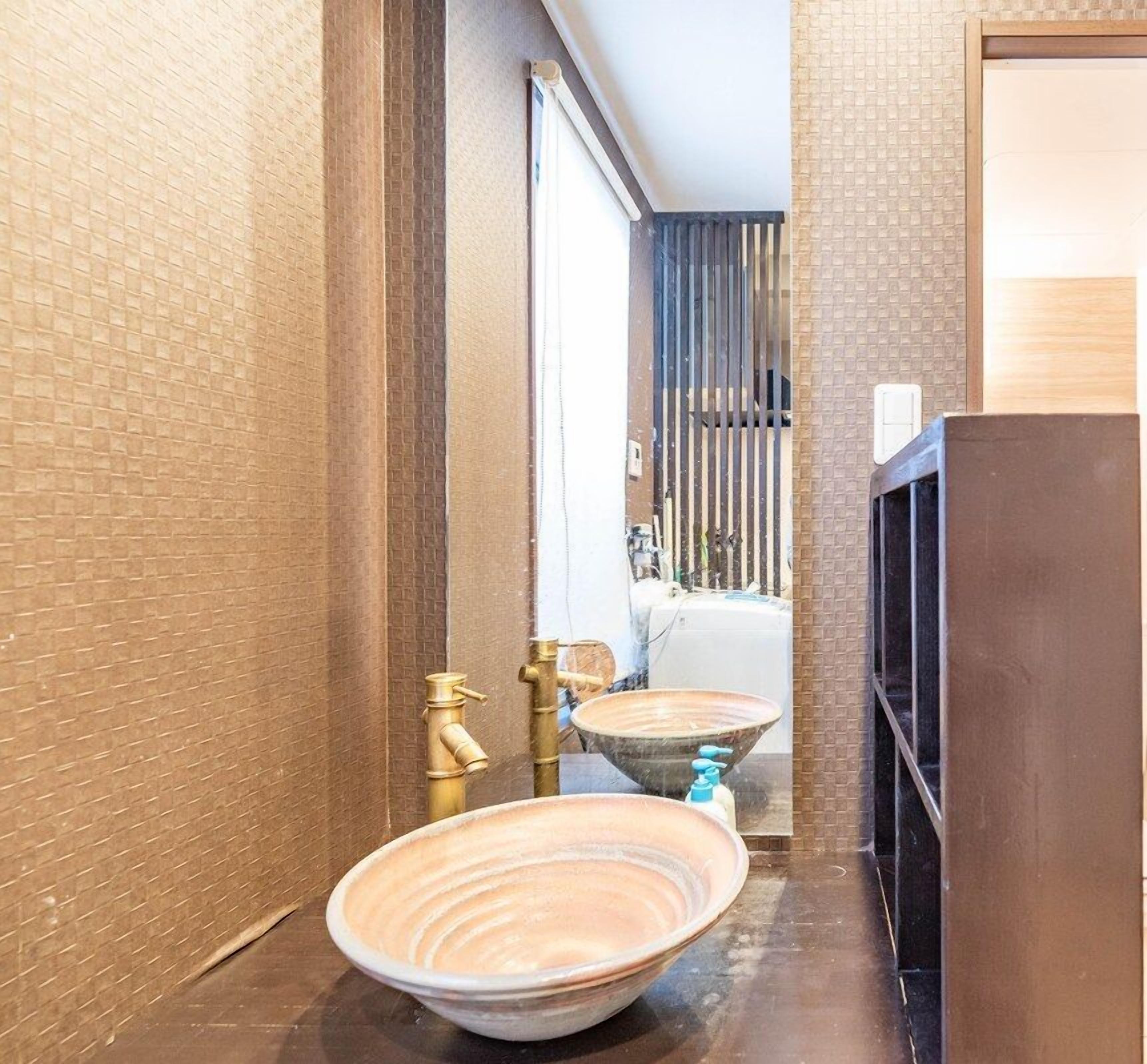 Une salle de bain avec deux grands lavabos en céramique, un robinet doré et un miroir.