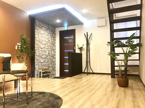 A modern interior with a stone wall, a wooden door, a standing plant, and a bar area.