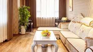 A living room with a wooden ceiling, a sofa, a coffee table with fruit, and a large plant.