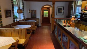 Um restaurante com cabines de madeira, um espaço de bar e vista através de uma porta em arco.
