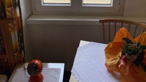 Quarto com janela para a rua, uma mesa com uma câmera e um buquê de flores.