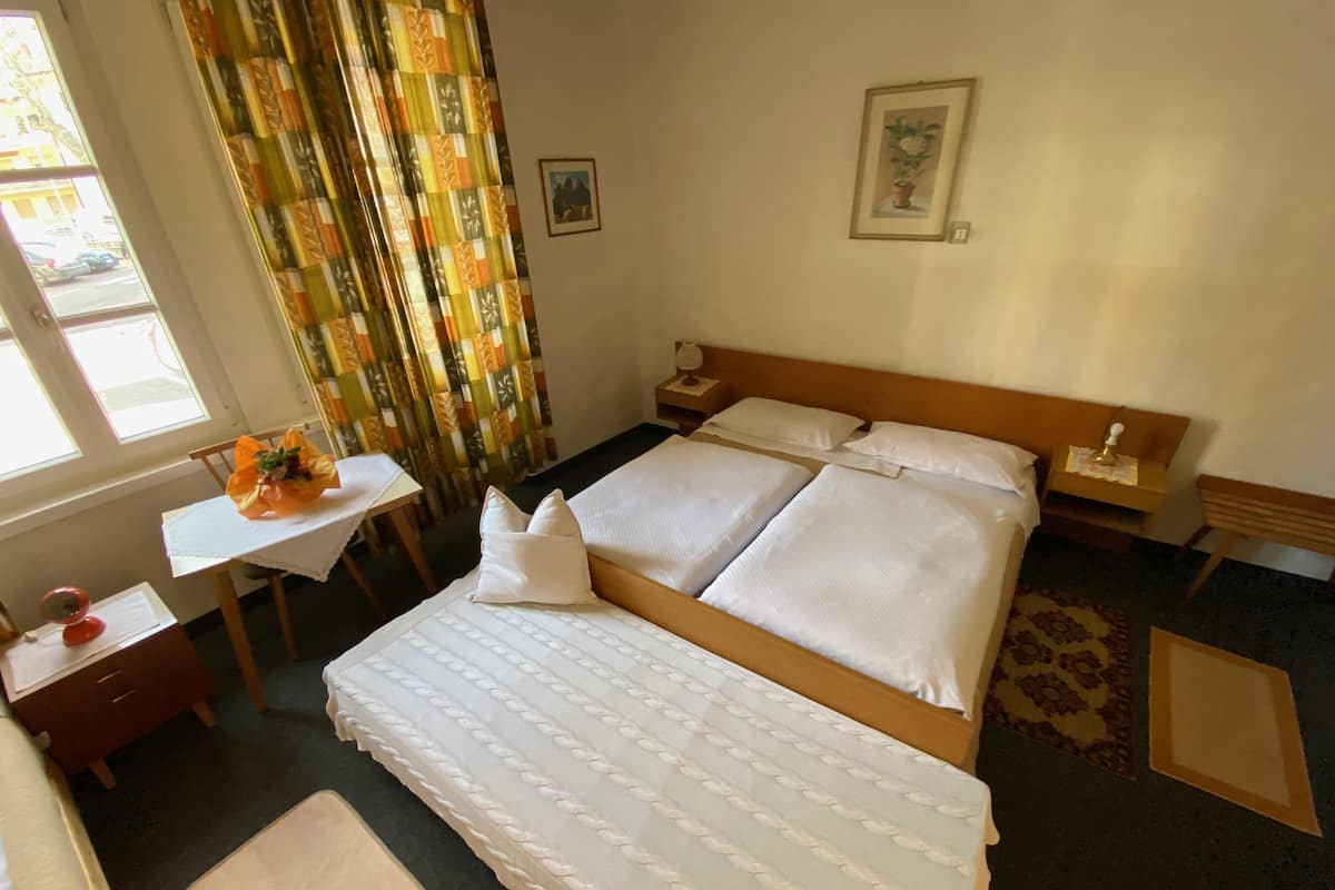 Ein Hotelzimmer mit einem Bett, einem Schreibtisch, einem Stuhl, einem Fenster und Vorhängen.