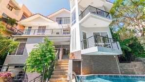 Une maison moderne à deux étages, dotée d’un balcon, d’une piscine et d’un escalier menant à l’étage supérieur.