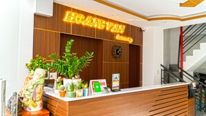 A reception desk with a wooden panel design, a neon sign reading "LENGYANG HOTEL", a clock, and various informational cards. - Hoang Van Homestay Nha Trang (Bac Nha Trang)