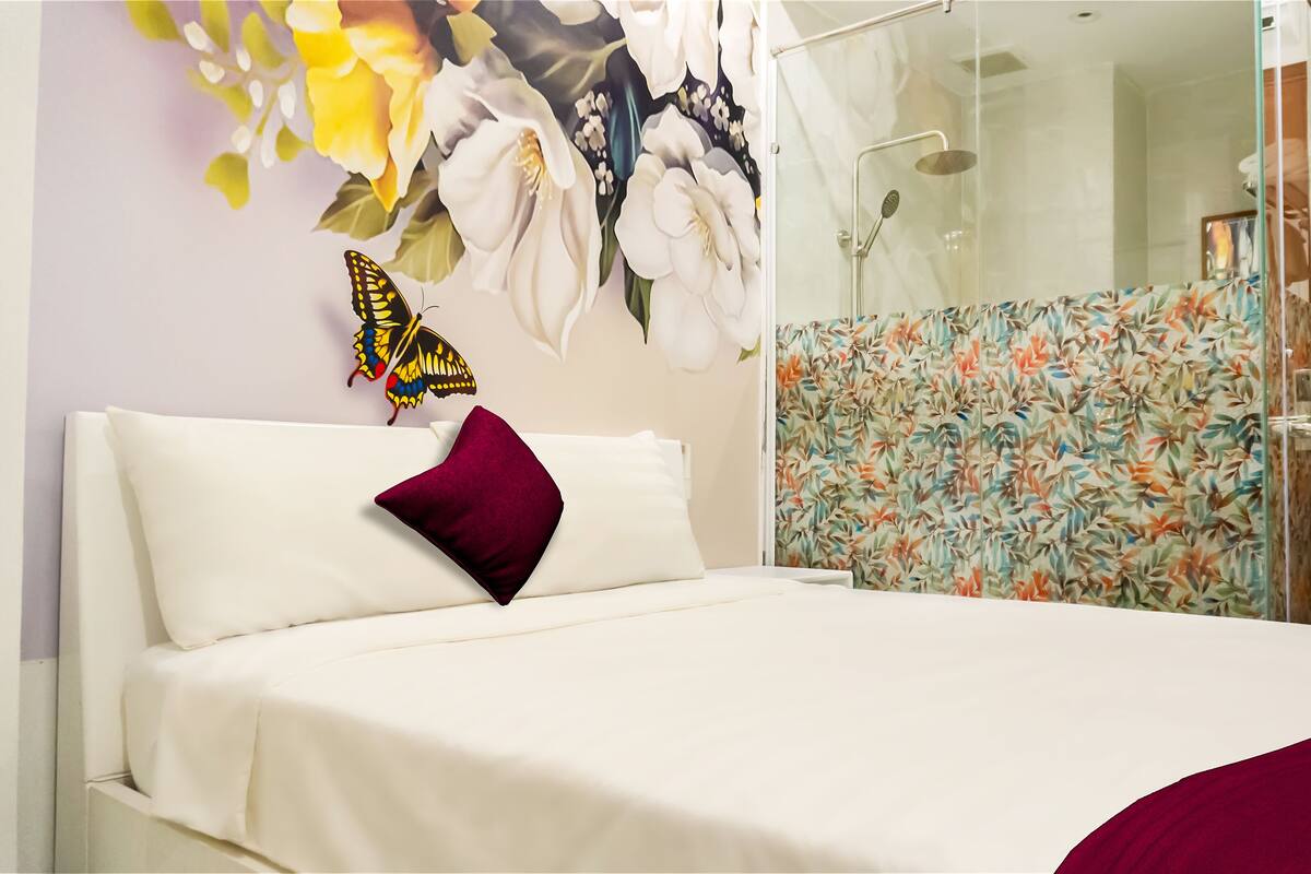 A hotel room with a bed, a shower area, and a door.