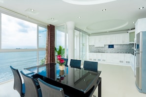 Una cocina moderna con armarios blancos, encimera negra y vista al mar.