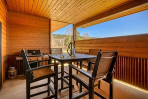 Un espace extérieur aménagé, abrité et doté d’un barbecue, de chaises et d’une vue sur le paysage.