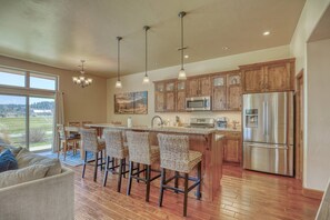 Una cocina amplia con gabinetes de madera, electrodomésticos de acero inoxidable y una zona de bar con sillas de mimbre.