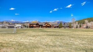 A large building with multiple rooms, a grassy field, and mountains in the background. - Steps to River, Yamaguchi Park, Air Conditioning and Downtown Fun! (Pagosa Springs)