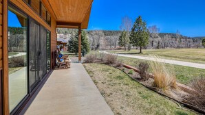 A modern building with large windows, a covered porch, and a view of a grassy field and trees. - Steps to River, Yamaguchi Park, Air Conditioning and Downtown Fun! (Pagosa Springs)