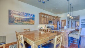 A spacious kitchen with wooden cabinets, a large island, and a dining area with a wooden table and chairs. - Steps to River, Yamaguchi Park, Air Conditioning and Downtown Fun! (Pagosa Springs)