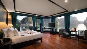 A spacious room with a large bed, a TV, and a view of the water. - Aspira Cruises (Tuan Chau)