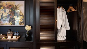 A dark wooden closet with a framed floral painting, a vase with flowers, and a tray with toiletries. - Aspira Cruises (Tuan Chau)