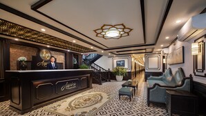 A lobby with a reception desk, a staircase, and seating areas. - Aspira Cruises (Tuan Chau)