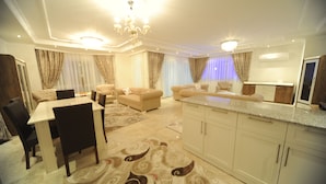 A spacious living area with a dining table, sofas, and a kitchen area. - Helena Villa (Alanya)