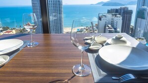 A dining table with a view of the ocean and cityscape. - Apartment Beach Nha Trang Sea View (Nha Trang)