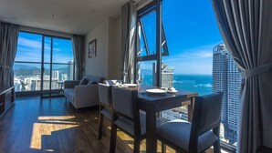 A modern hotel room with a large window offering a city and ocean view. - Apartment Beach Nha Trang Sea View (Nha Trang)
