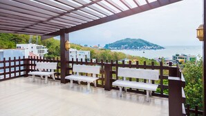 An outdoor patio with white benches and a view of a coastal cityscape. - Villa Seaview 1 (Ho Chi Minh City)