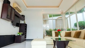 A modern living room with a glass coffee table, beige sofa, and a dark wooden cabinet. - Villa Seaview 1 (Ho Chi Minh City)