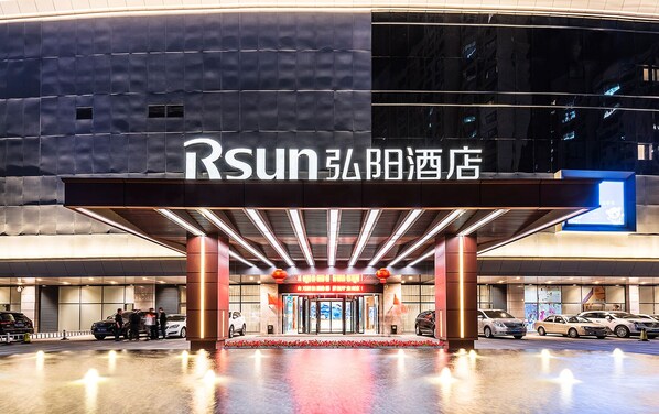 A modern hotel entrance with a prominent sign and a well-lit facade.
