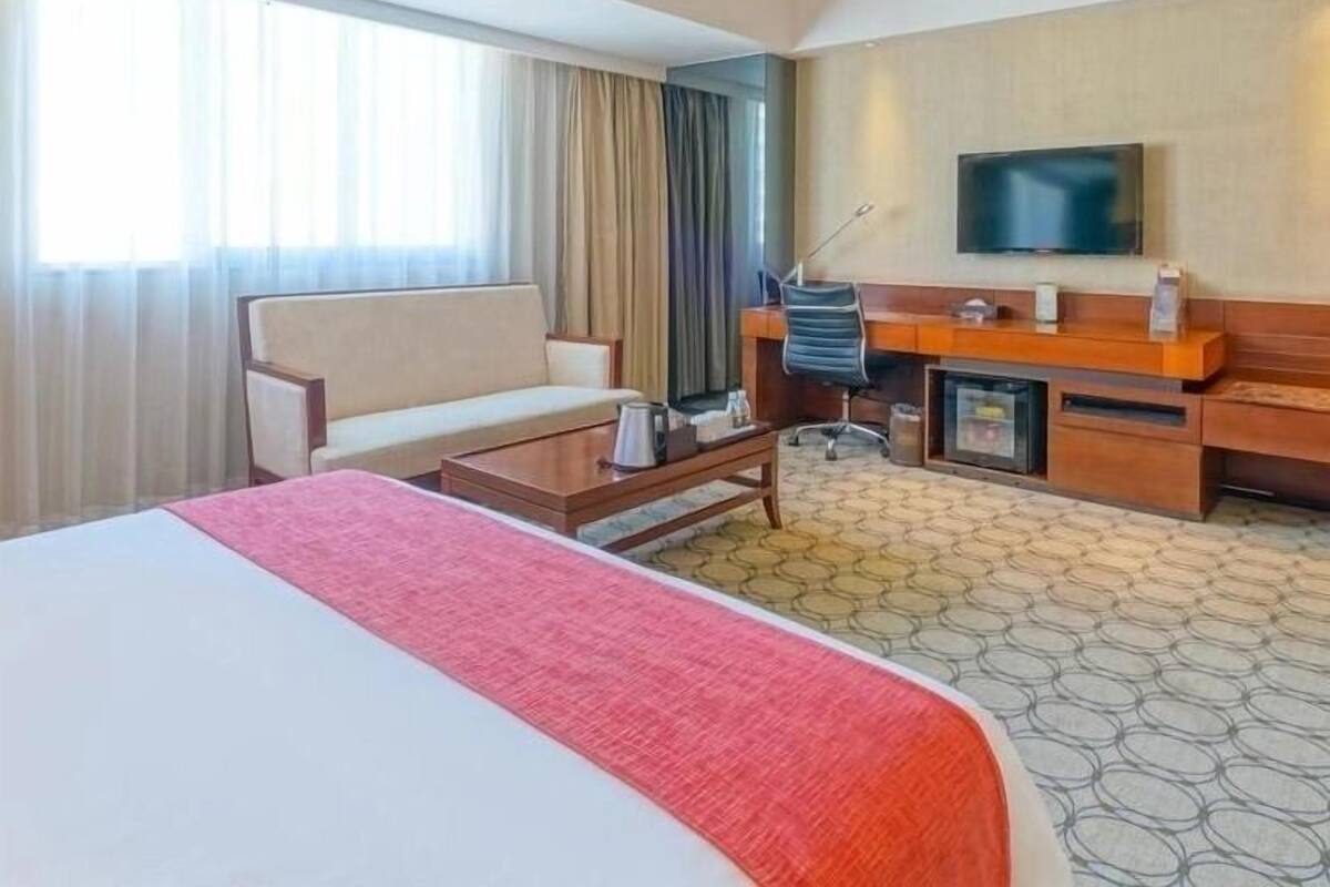 Een hotelkamer met een groot bed, een bank, een bureau met stoel, een televisie en een salontafel.