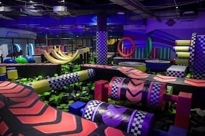 An indoor play area with various colorful play structures and obstacles.