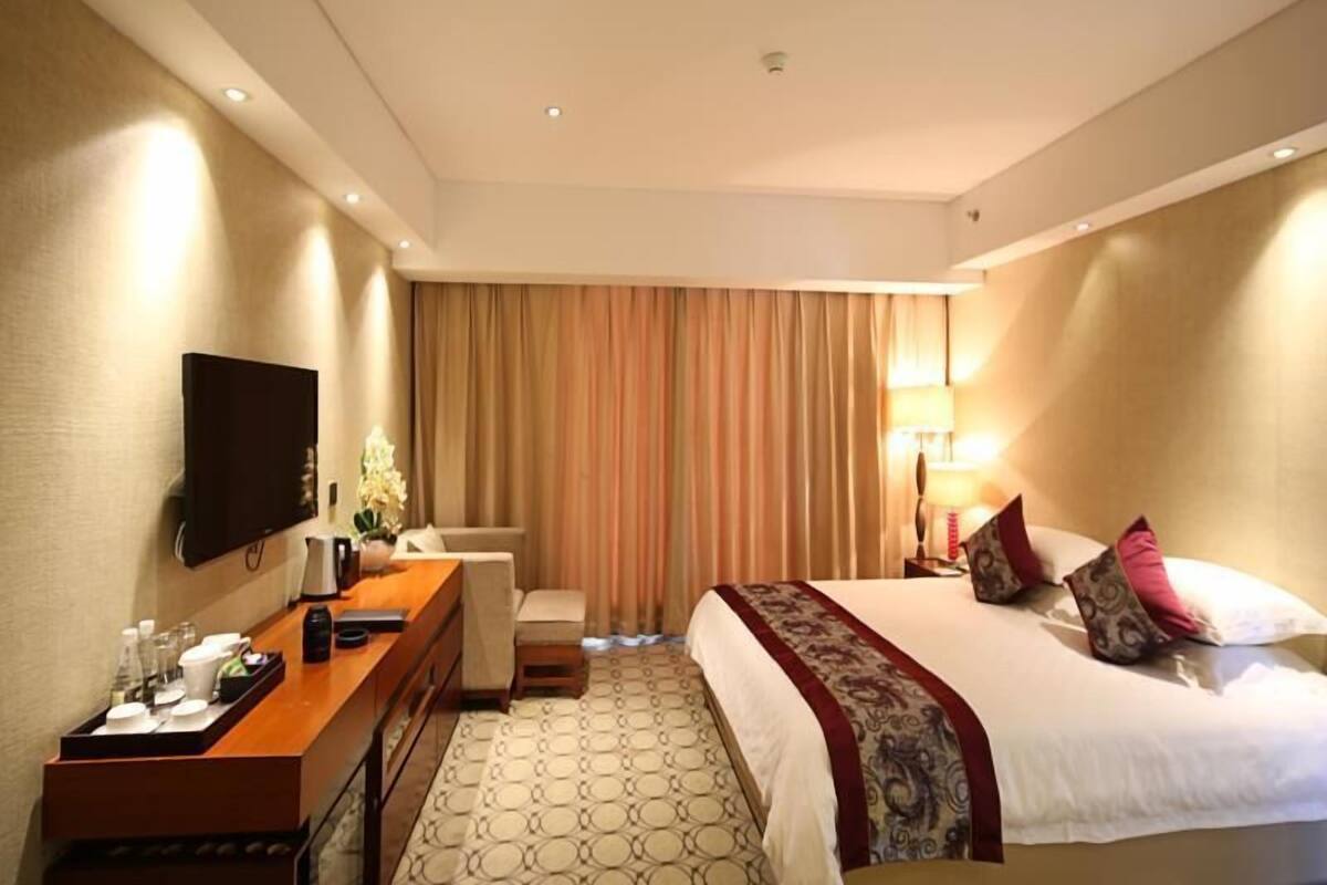 Een hotelkamer met een bed, nachtkastje, televisie en bureau met stoel.