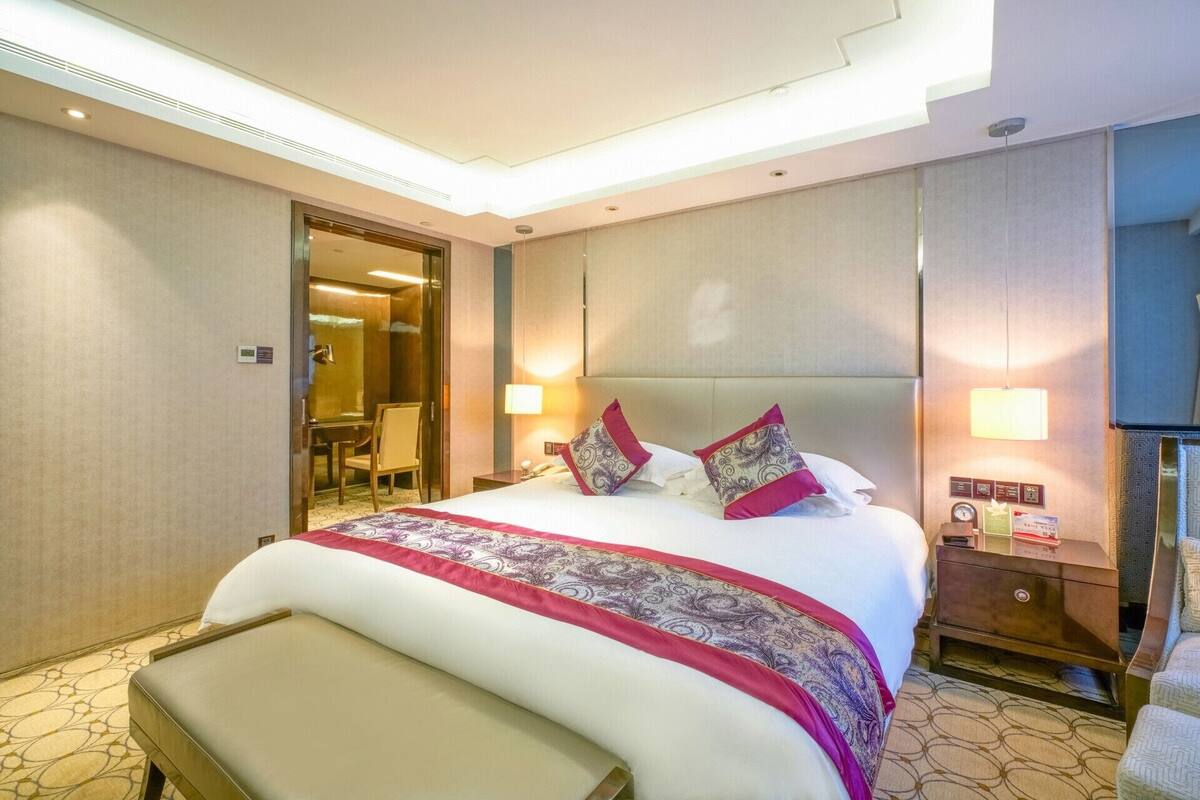 Een hotelkamer met een groot bed, nachtkastjes, een bureau en een stoel.