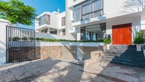 A modern multi-story building with a red door, stone steps, and a gated entrance. - Villa Viba (Ho Chi Minh City)