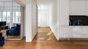 A modern apartment with a living area, kitchen, and a hallway leading to a door. - Tigli (Lugano)