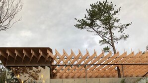 A modern building with a unique wooden lattice roof and a staircase leading up to it.