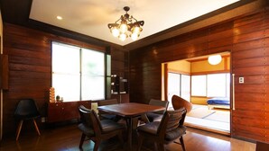 A traditional Japanese-style room with a wooden interior, a tatami mat room, and a dining area with a table and chairs.