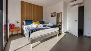 A modern bedroom with a bed, bedside table, and a door. - Résidence Calarossa Bay Resort (Lecci)