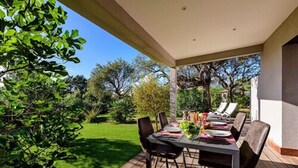 An outdoor dining area with a table set for four, surrounded by chairs, on a wooden deck. - Résidence Calarossa Bay Resort (Lecci)