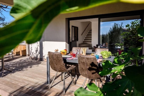 An outdoor dining area with a table set for two, surrounded by chairs, and a staircase leading to an upper level.