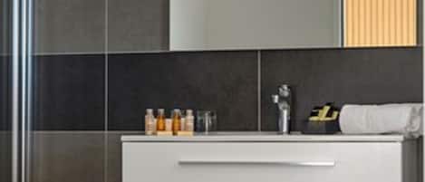 A modern bathroom with dark tiles, a white vanity, and a mirror.