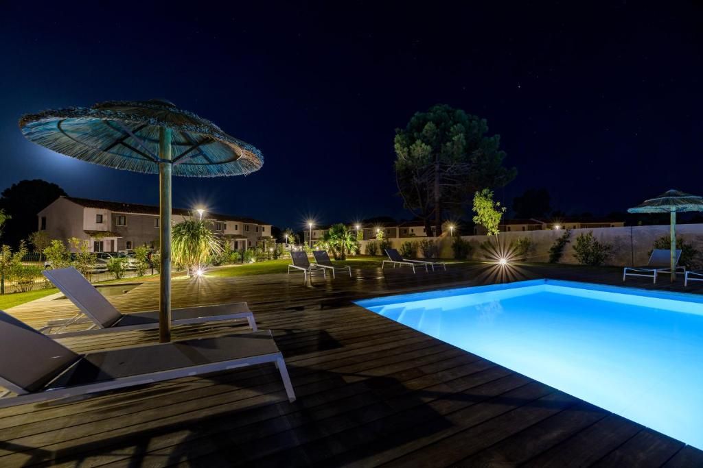 A swimming pool area with lounge chairs and umbrellas.