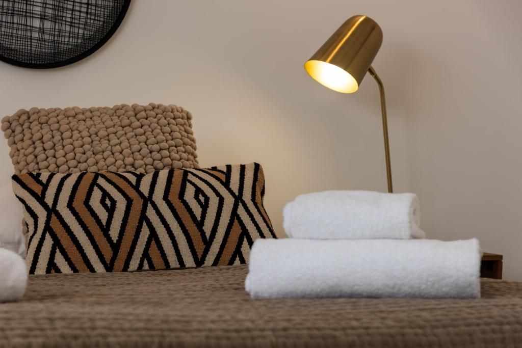 A bed with a patterned pillow, a round wall decoration, and a bedside lamp.