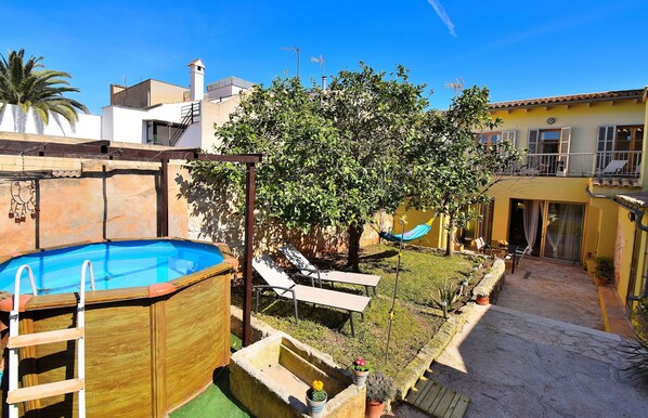 A backyard with a swimming pool, lounge chairs, a hammock, and a small garden.