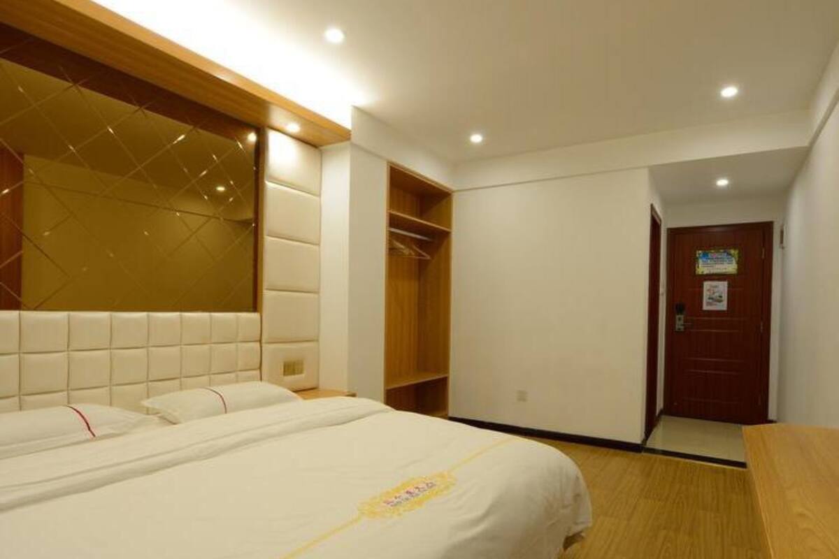 A hotel room with a large bed, a wooden headboard, a wardrobe, and a door with a sign.
